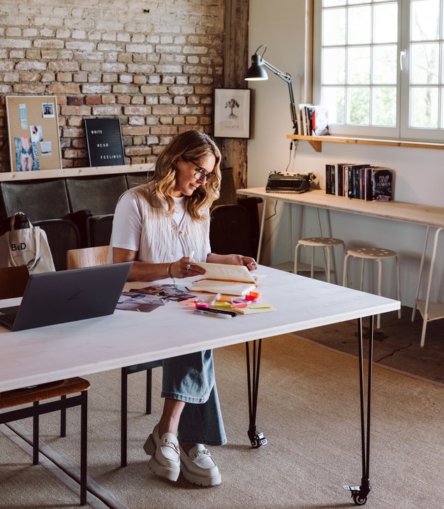 Frau sitzt am Schreibtisch und arbeitet